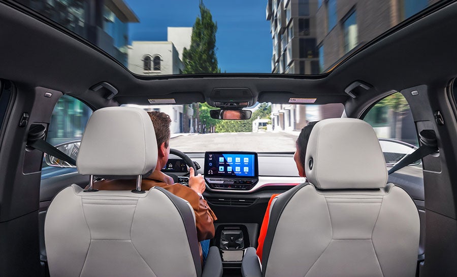 A forward facing shot of an ID.4 with focus on the driver and passenger seats, center console display, and available panoramic sunroof.